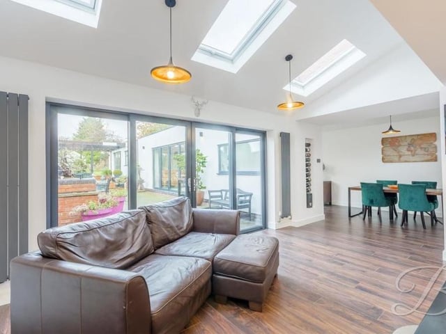 This image shows how the large bi-folding doors lead from the kitchen's living space to the garden. The dining room is in the background.