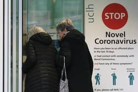Two women walk past a sign providing guidance information about novel coronavirus (COVID-19) at one of the entrances to University College Hospital in London. (Photo by ISABEL INFANTES/AFP via Getty Images)