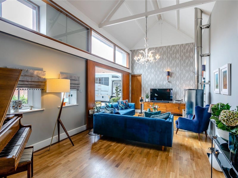 The sitting room features a unique piece of architectural design in a glass sliding wall which opens up into the courtyard to the front of the property.