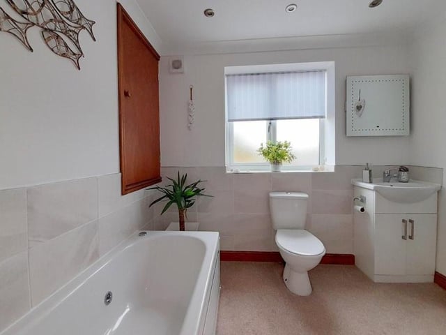 The family bathroom on the first floor includes a panelled spa bath with a shower attachment to the mixer tap. There is also a low-flush WC and pedestal wash hand basin, while a cupboard houses a gas combi boiler.