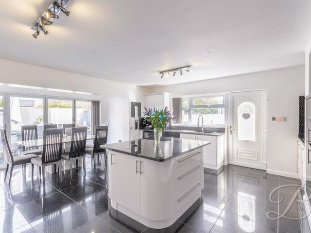 Opposite the living room sits this gorgeous kitchen/diner, which boasts a range of gloss wall and base units, integrated appliances, and a handsome, granite-topped central island.with pop-up electric points. The dining area, which you can see to the left, is next to bi-fold doors that lead out to the back garden.