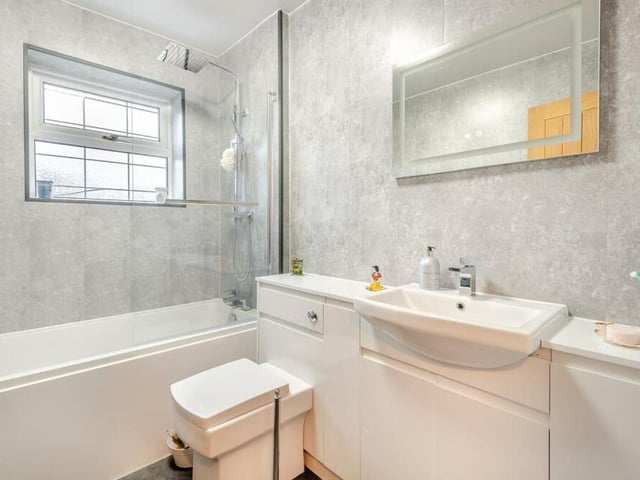 Completing our look at the first floor is this family bathroom, which features a panelled bath with mixer tap and rainfall shower over. It also includes a vanity unit with inset wash hand basin and storage cupboard beneath, low-flush WC and heated towel-rail.