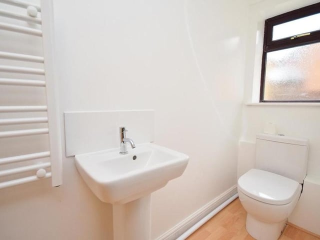 The ground floor of the Ravenshead property also features this cloakroom. It contains a low-level WC, pedestal wash basin, heated towel-rail and laminate flooring.
