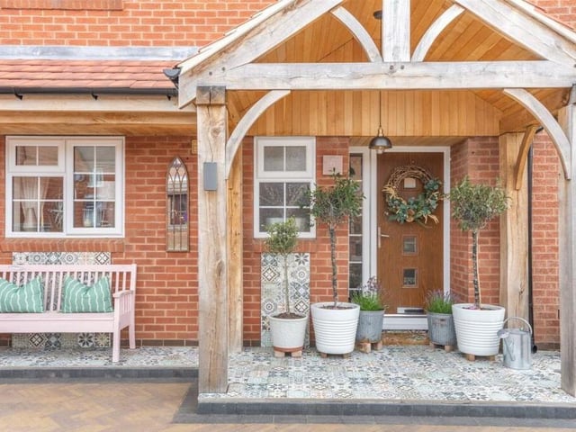 The front of the property is distinguished by this welcoming green oak canopy storm porch, complete with porcelain tiled floor that extends across the full width of the house.