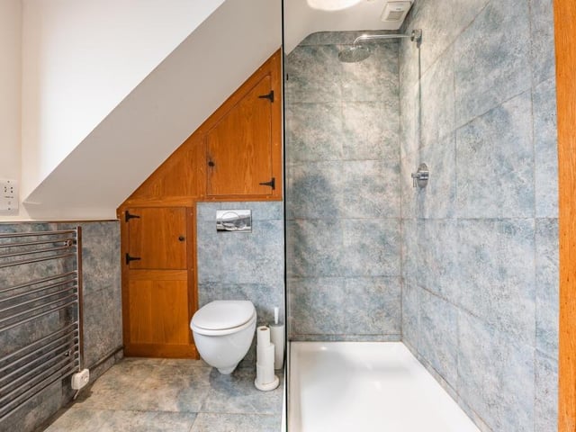 The family bathroom also features a walk-in shower enclosure, a WC and cute oak storage cupboards.