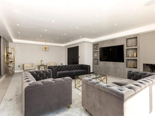 The intimate living room is anchored by a bespoke media wall that combines high-end aesthetics and technology.