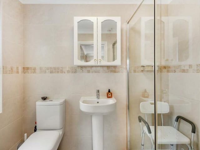 Here is the en suite shower room to the master bedroom. A modern three-piece suite with chrome fittings consists of a large, tiled shower enclosure with electric Mira shower and sliding doors, a pedestal wash hand basin and low-flush WC. There is also chrome, heated towel-rail and attractive tiling.