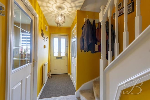 In we go to the Cambourne Place house, finding ourselves in this warm and welcoming entrance hallway, which features a carpeted floor and a central heating radiator. Of the doors pictured, one leads to the kitchen and the other to the downstairs toilet.