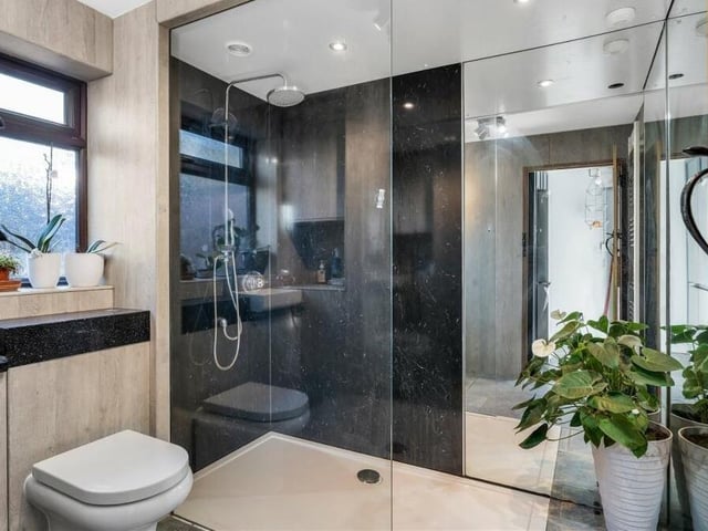 The ground floor of the terraced cottage includes this modern shower room. As well as a double walk-in shower, it features a vanity unit, low-flush WC, built-in cupboard, heated towel-rail and porcelain tiled floor.