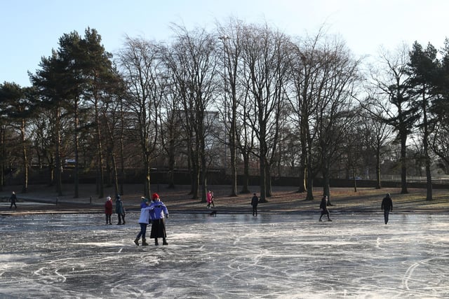 People walk on a frozen pond at Victoria Park