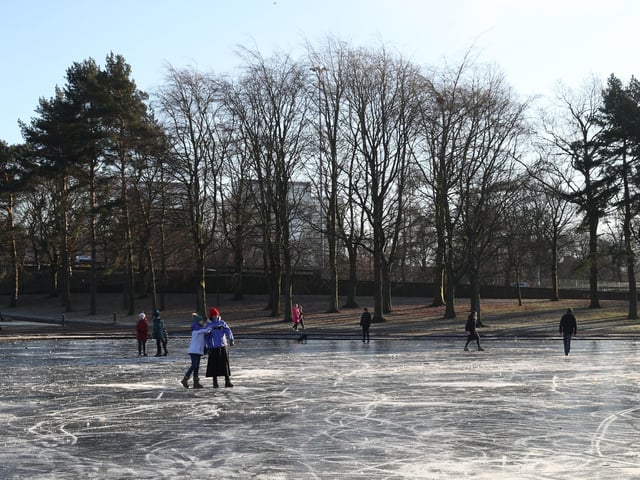 People walk on a frozen pond at Victoria Park