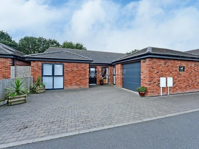 The final photo of our gallery returns to the front of the property to show the off-street parking space on the driveway and also the large garage, which is fitted with a wide electric door that measures ten feet by eight feet. For extra security, the bungalow is fitted with a CCTV system.