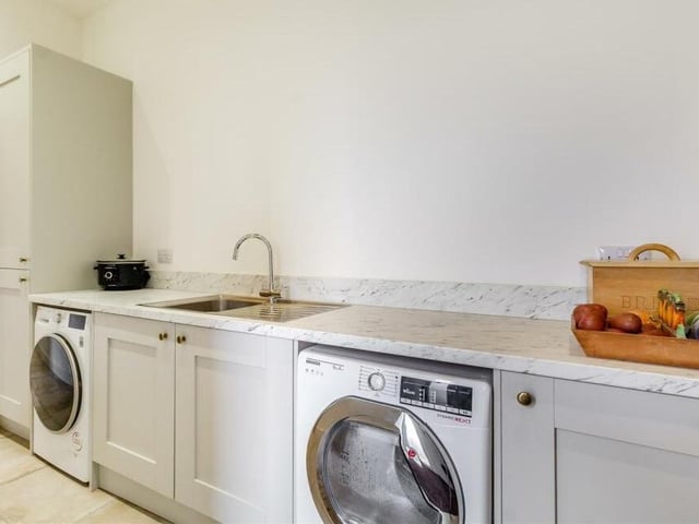 Just off the dining kitchen is this handy utility room, which has plumbing for a washing machine and space for a tumble dryer. Modern shaker cabinets comprise wall cupboards and base units with quartz-effect worktops above and a stainless steel sink
