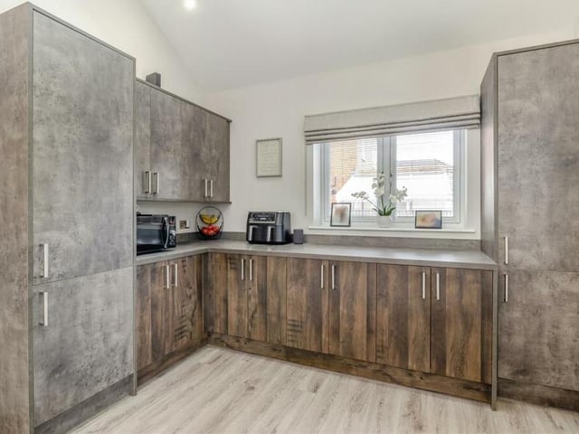 The kitchen features a range of modern cabinets, with brushed chrome handles. They comprise wall cupboards, base units and drawers, all complemented by dark wood-style worktops. Double-glazed windows face the side and back of the property.