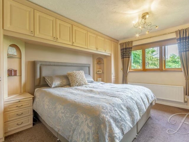 The master bedroom boasts over-bed storage with fitted wardrobes and drawers, plus additional fitted wardrobes. The floor is carpeted, and there is access to an en suite bathroom.