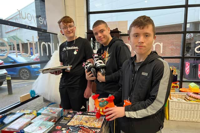 Students (left to right) Brandon Ellis, Caiden Roberts and Thomas Ward create a window display.