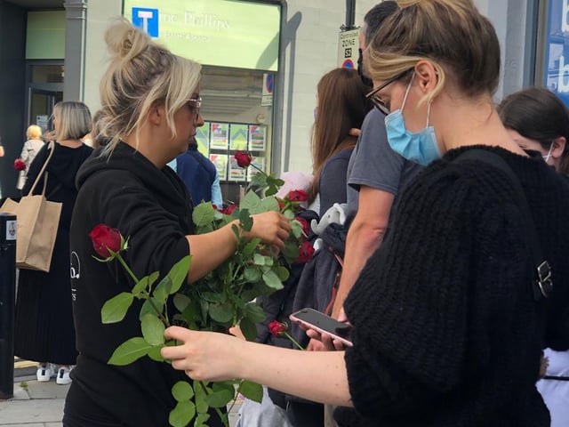Girls were seen to be passing out the red roses to those waiting on the cortege