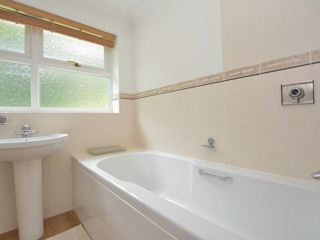 Here is the family bathroom on the first floor. A modern Jacuzzi three-piece suite with chrome fittings is made up of a panelled bath with mixer tap and wall-mounted shower above, pedestal wash hand basin and low-flush WC.