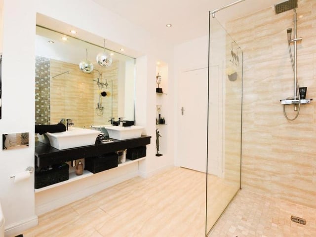 Next stop on our tour of the £750,000-plus dormer bungalow is this family shower room/wet room. A contemporary suite comprises a low-level WC, Mr and Mrs wash hand basins with mixer taps, and a shower with waterfall shower and an additional shower attachment and screen. There are also recessed spotlights and a door to one of the bedrooms.