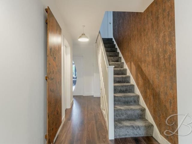 Time to head upstairs now, so it's back to the entrance hall with its oak flooring, cupboard for extra storage and carpeted staircase to the first floor.