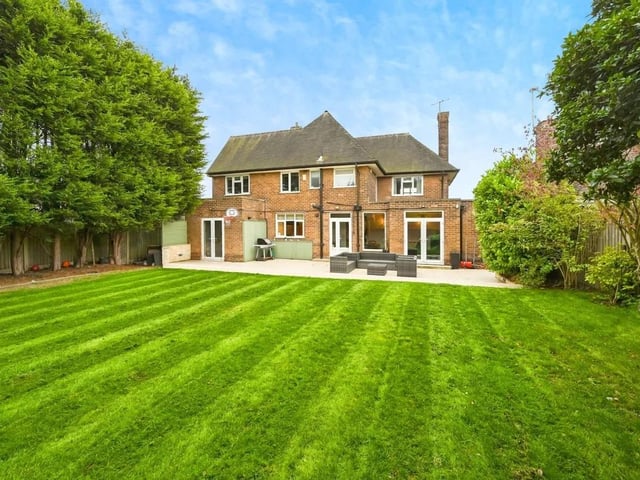 The rear garden offers a private, enclosed space with mature trees and shrubs, a large patio area, and lawn - perfect for relaxing or entertaining outdoors.