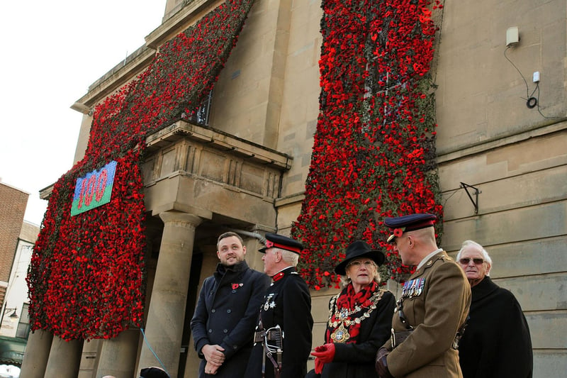 Mansfield's Executive Mayor, Coun. Kate Allsop joins other dignitaries in front of the old Town Hall, festooned in 16,000 hand knitted poppies before taking the salute.