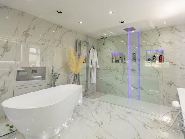 Here is a close-up of the designer en suite bathroom to the master bedroom. An incredible, modern suite consists of a standalone bath with waterfall tap, spacious walk-in shower cubicle with waterfall shower, low-flush WC, double vanity hand wash unit, full-sized, mirrored TV, downlights, underfloor heating and floor-to-ceiling marble tiling. Wow!