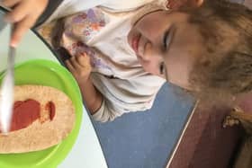 Three-year-old Esmae Aitken spreads some tomato puree on her pizza.