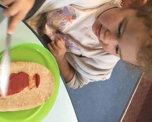 Three-year-old Esmae Aitken spreads some tomato puree on her pizza.