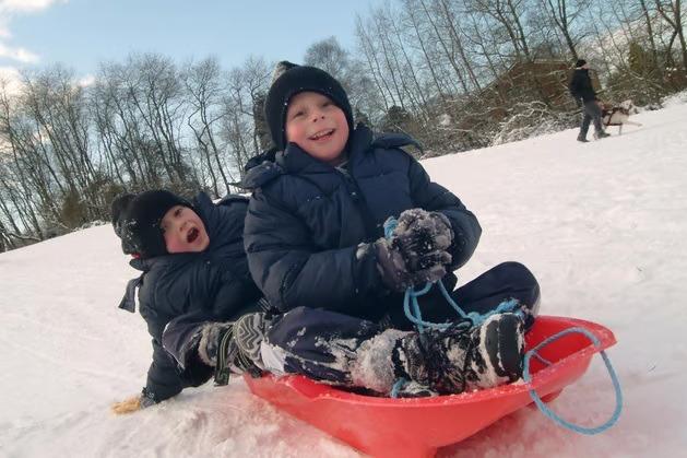 Friends Daniel Brown and Jack Shipman, both 6, from Sutton sledding together in the snow on Sutton Lawn in January 2010