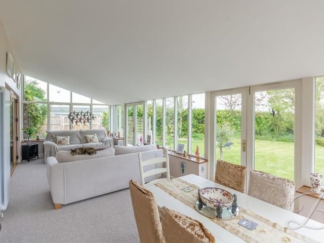 There are two conservatories on the ground floor of the Derby Road house, including this one, which has space for a living area and a dining area. Surrounding windows overlook the garden, and a set of double doors lead outside.