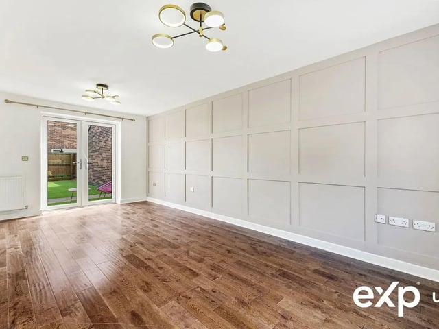 The cosy yet spacious lounge with panelled feature wall and French doors to the garden.