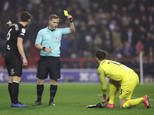 Nathan Baxter of Hull City is shown a yellow card by referee John Busby. That is one of 67 bookings for Hull this campaign.