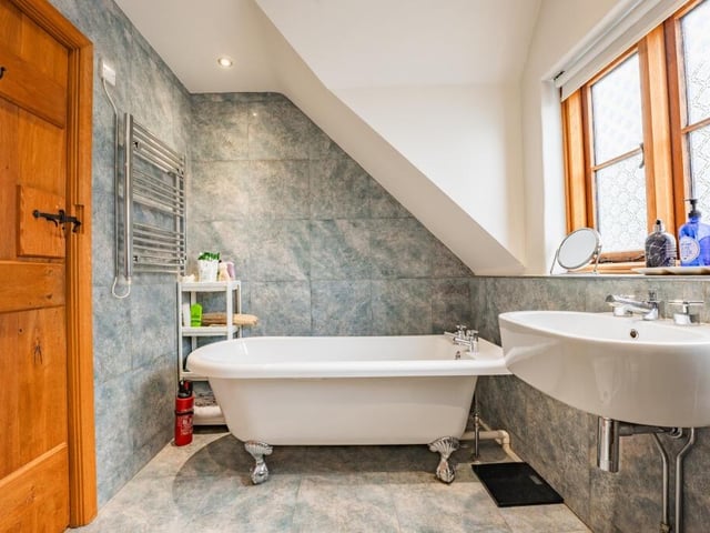 A feature roll-top free-standing bath dominates the modern family bathroom on the first floor. The room is finished with blue porcelain tiles and has underfloor heating and two heated towel-rails.