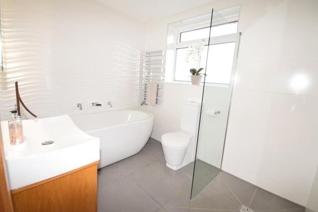 Our last photo from the Ravenshead property shows the family bathroom. Quality is not compromised in a suite comprising a double-ended bath with waterfall tap, walk-in shower with rainfall shower head, wash basin with double-drawer vanity unit and low-flush WC. The floor and walls are tiled, and there is also a chrome, heated towel-rail.