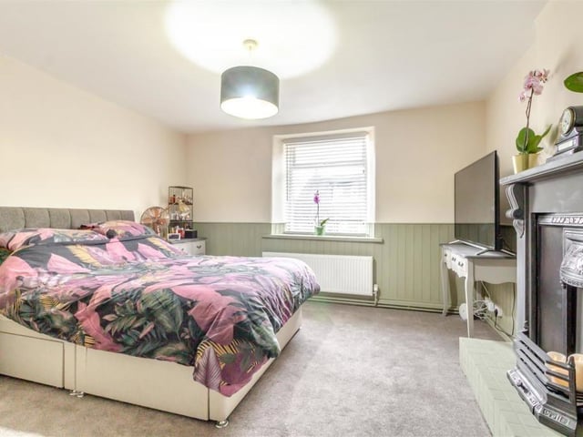 The master bedroom at the Whitwell house is spacious, with panelled walls painted lichen by Farrow and Ball. The window overlooks the front of the property, and there is plenty of room for wardrobes and storage.
