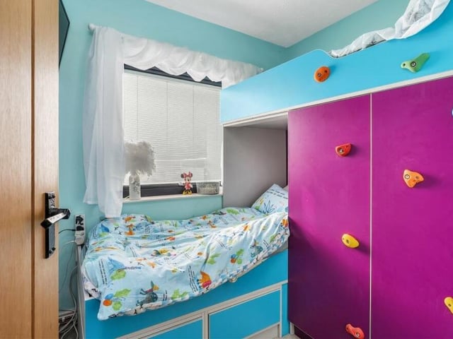 This bedroom, which overlooks the back garden, is ideal for a child. It features built-in cupboards.