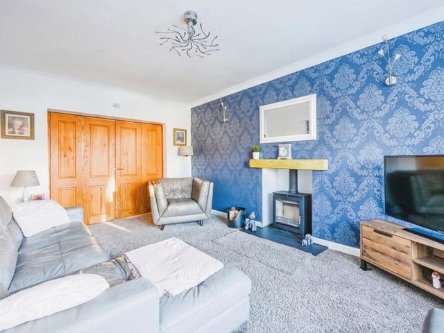 The Kirkby property's second reception room is this comfortable lounge, which is distinguished by a bay window to the front of the house and a feature fireplace with multi-fuel burner. The floor is carpeted.