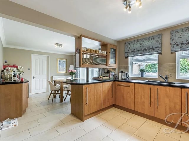 The kitchen hosts a stunning range of cabinets and units with modern work surfaces above, integrated appliances and splashback tiles.