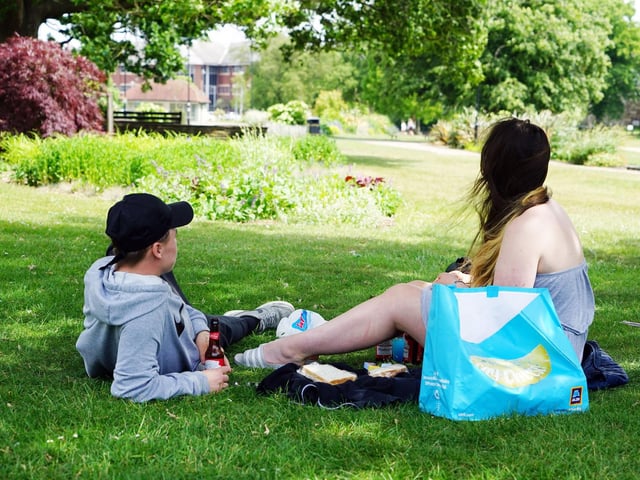 Two people enjoy lunch in the sunshine.