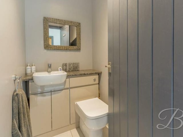 By the utility room is this well-presented toilet, with WC, hand wash basin and storage space.
