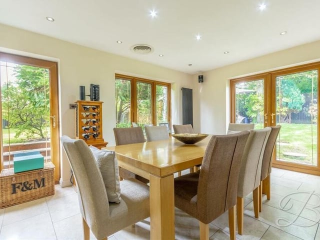 The bright dining area is surrounded by large windows or patio doors, making the kitchen ideal not just for cooking but also for entertaining,