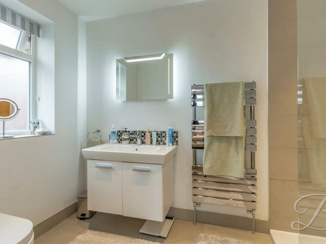 For added luxury, two of the bedrooms have their own private en suite facilities. Here is one, comprising a walk-in shower cubicle, low-flush WC, vanity hand wash basin and chrome, heated towel-rail.