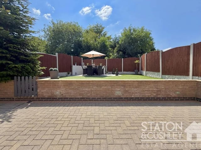 Beautifully landscaped for ease of maintenance, it offers a generous patio seating area, perfect for outdoor dining and entertaining during the warmer months, with steps leading to an artificial lawn that provides year-round enjoyment.