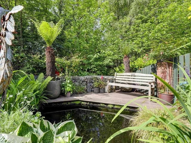 Beautifully established planting, mature trees, decorative pathways and ornamental borders surround a stunning stream-fed pond with cascading water features.