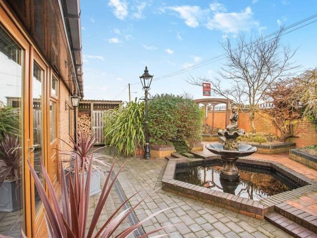A second shot of the central water feature in the front garden, which also includes several stocked, bedded planting areas and a side gate and path leading to the back of the property.