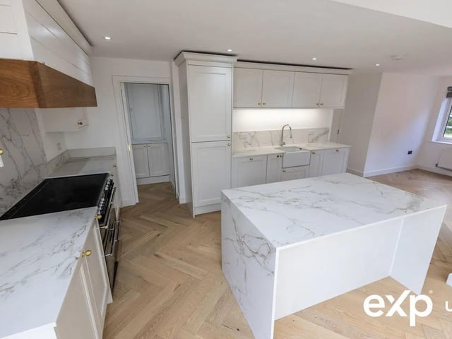 The kitchen area boasts marble-effect worktops, shaker-style cabinetry, herringbone flooring.