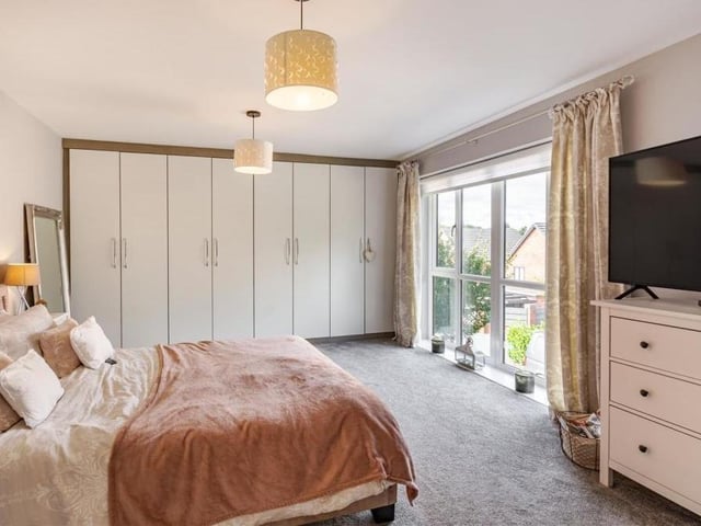 The second bedroom is distinguished by its extensive, modern fitted wardrobes to one wall and its large floor-to-ceiling window that overlooks the front of the property.