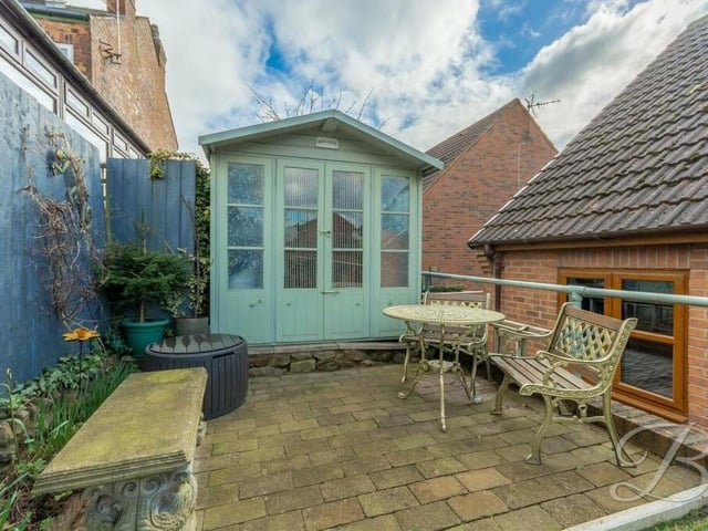 Here is a close-up of the pleasant patio area at the far end of the back garden. It sits in front of an outbuilding that could be deployed as a summer house,