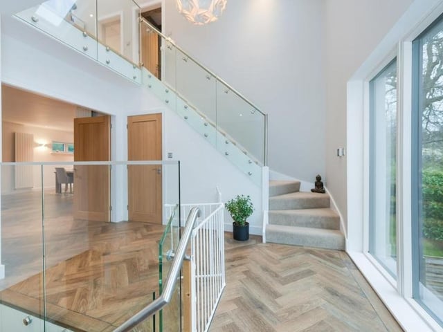 On the first floor, there is an open landing with full-height windows that allow natural light to flood the space.